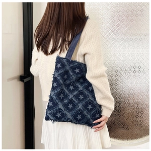 Detail of denim tote bag with frayed star patches and large capacity shoulder design