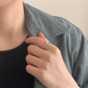 Detail shot of silver smile engraved open ring worn on finger over gray shirt