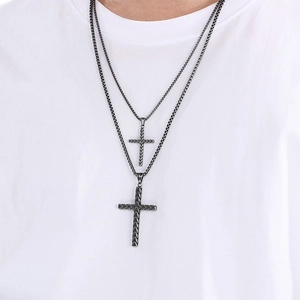 Gros plan d'une double chaîne en acier noirci avec pendentifs croix portés par un mannequin