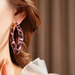 Detail of a large leopard print hoop earring with pink and black leather texture