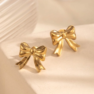 French vintage matte gold bow earrings with elegant brushed metal texture on stone stand