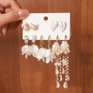 Detailed set of pearl stud earrings and gold floral tassel pendants on white card