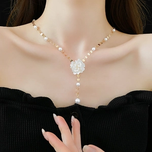 Detail of elegant gold Y-shaped necklace with flower pendant and white pearls on model