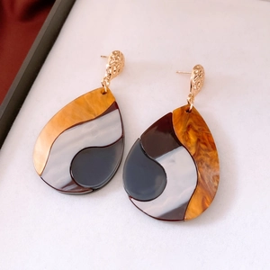 Vue macro de boucles d'oreilles irrégulières en résine ambre et blanc perle
