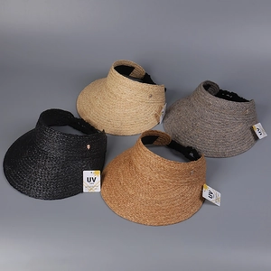 Detail view of four-color straw open-top sun hats with UV protection tags in flat lay