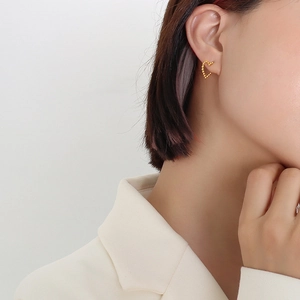 Minimalist gold heart-shaped stud earrings with beaded texture on professional model