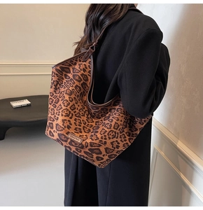 Detailed side view of large leopard print tote bag with brown fabric and black shoulder straps