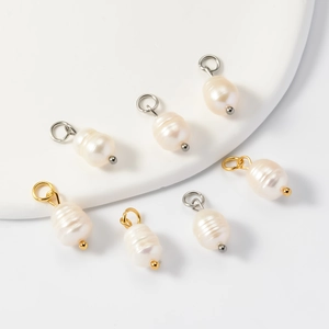 Irregular natural freshwater pearl pendants with gold and silver loops on white pedestal
