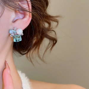 Detail of square blue gemstone earrings with white pearls and silver needle setting