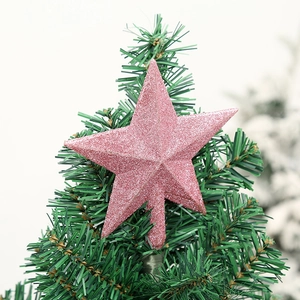 Close-up of pink glittered Christmas tree topper star on a green branch