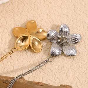Détail des colliers avec pendentif fleur plaqué or 18 carats et argent sur surface texturée
