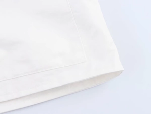 Detailed close-up of white twill fabric with double-stitched seams on the hemline