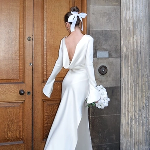 Elegant white satin evening gown featuring an open back design and long flared sleeves