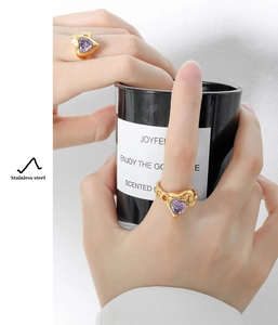 Macro detail of a gold stainless steel ring with a purple heart-shaped zircon stone