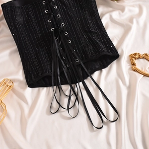 Detail of black corset top with silver glitter stripes and front lace-up fastening