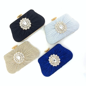 Detailed view of pleated silk evening clutch bags in four colors with crystal floral brooch