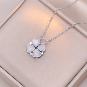 Silver four-leaf clover necklace with white heart-shaped stones on champagne jewelry box