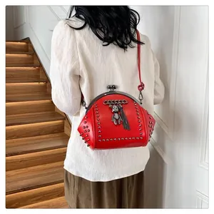 Macro detail of red shell bag featuring rivet studs, bear charm and vintage clasp