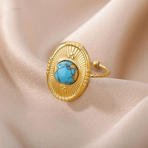 Detail of vintage gold ring with turquoise stone and sunburst engraving on silk fabric