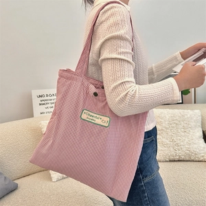 Detail of red and white checkered canvas tote bag featuring a green Cheerful Sozakka label