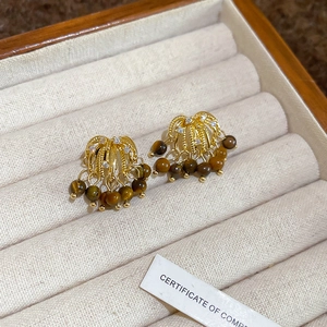 Detail of golden tassel earrings with brown tiger eye beads in a velvet jewelry box