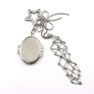 Detailed macro view of silver metal keychain with star clasp, bow charm and mesh tassels