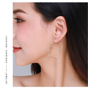 Fashion model wearing large minimalist silver heart-shaped hoop earrings for women