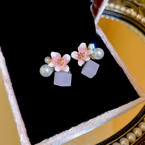 Macro view of flower stud earrings with pearl accents and lavender cube pendants