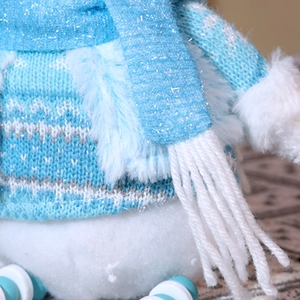 Dettaglio ravvicinato della trama a maglia e della sciarpa blu del pupazzo di neve di peluche