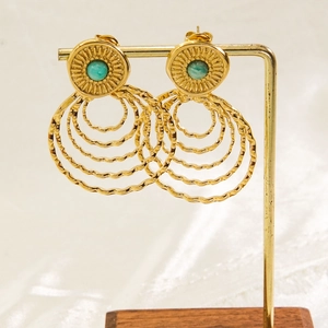 Detailed view of bohemian gold wave hoop earrings with turquoise stone on display
