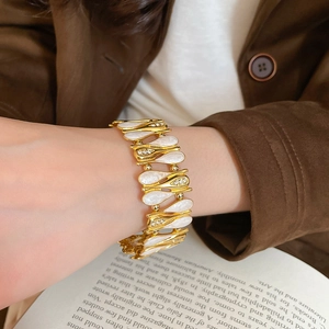 Detail of a vintage gold bracelet featuring pearly white drop charms and sparkling rhinestones