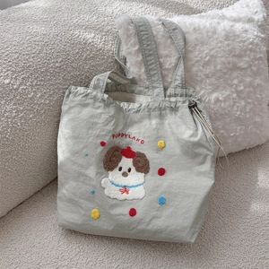 Detail of light green canvas tote with cute puppy embroidery and drawstring closure