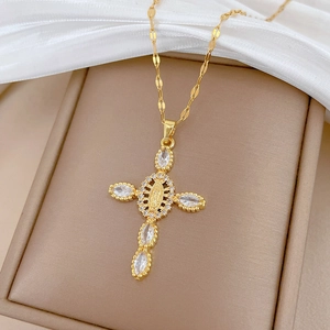 Detailed close-up of a gold cross pendant with Virgin Mary relief and clear crystals
