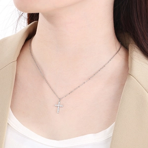 Close-up of a silver rhinestone cross pendant necklace worn on the collarbone