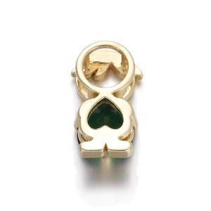 Macro shot of gold heart-shaped pendant with an emerald green stone inlay on white surface