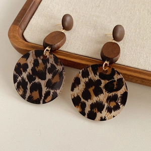 Detail of leopard print resin earrings with dark brown wood beads on beige linen