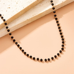 Bohemian gold chain necklace with black faceted resin beads on textured stone tiles