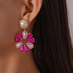 Dettaglio ravvicinato di orecchini a fiore con cristalli rosa e perno quadrato con perla