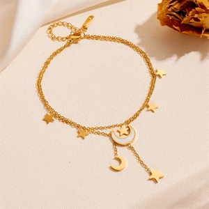 Detailansicht der goldene mehrlagige Fußkette mit Mond und Sternen auf Satin