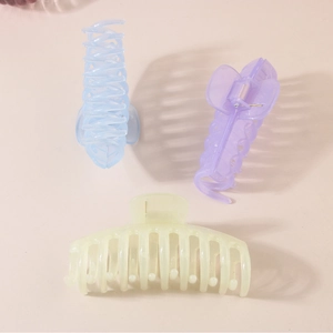 Three candy-colored jelly hair clips in blue, purple, and cream on pink background