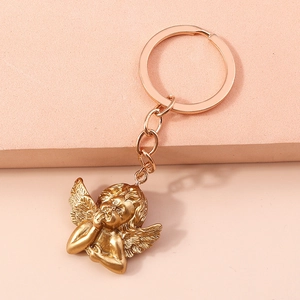 Detail of matte gold angel keychain with wings on a decorative pink stepped display