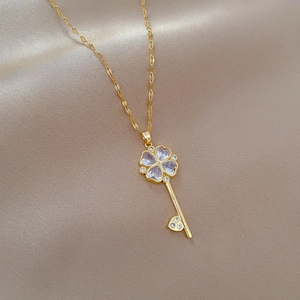Close-up of gold key necklace featuring purple zircon clover and silk background