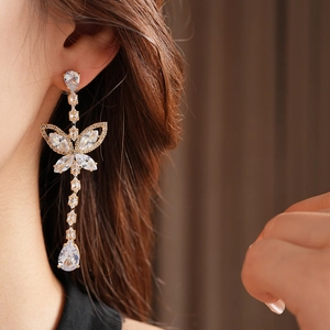 Detail of gold butterfly drop earrings with clear zircon crystals on model