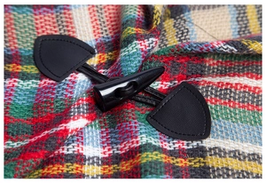Detail of classic horn buckle and plaid wool fabric on kids' hooded poncho cape