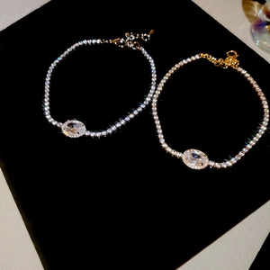Detailed macro view of gold and silver zircon oval bracelets on black velvet display
