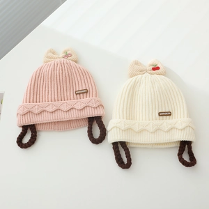 Détail de bonnets tricotés pour bébés avec nœuds cerise et tresses de perruque douces