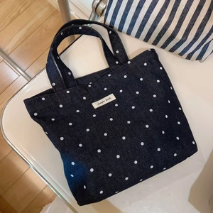 Close-up of a blue denim tote bag with white polka dots and simple wish label