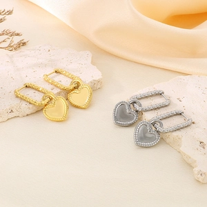 Détail de boucles d'oreilles cœur en or et argent sur un support en pierre