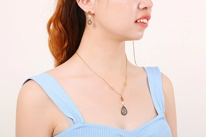 Detail of leaf-shaped gold necklace and earrings set with teardrop zircons on a model