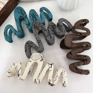 Matte finish wavy claw clips in diverse colors with artistic splatter ink patterns